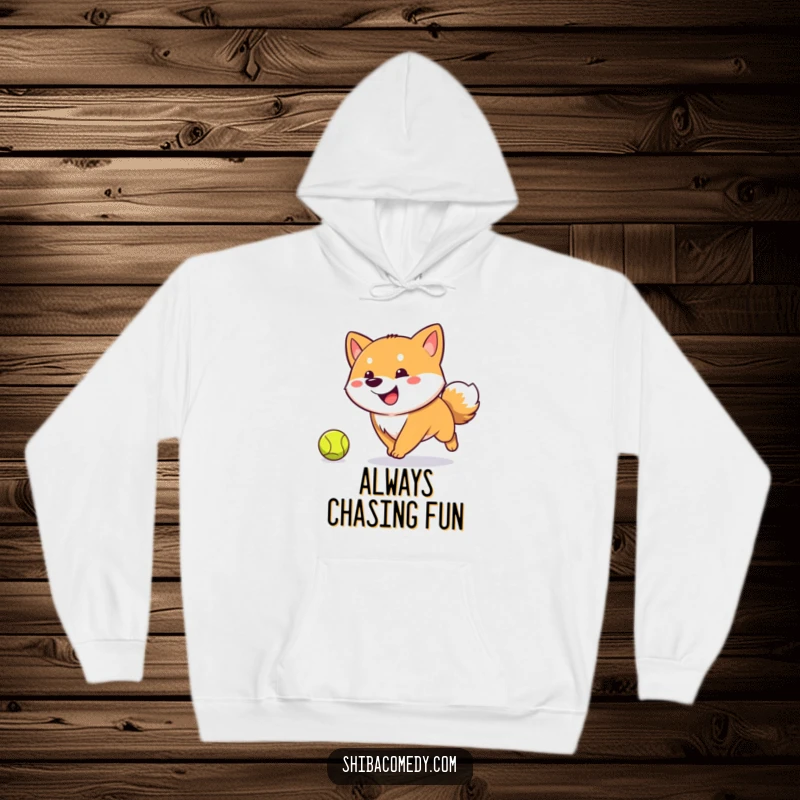 Funny Shiba Inu hoodie featuring a happy, tail-wagging dog intensely chasing a tennis ball, offering warmth and playful energy.